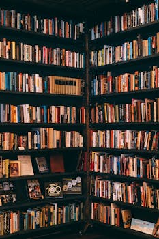 Corner view of a library with dark wooden bookshelves filled with a variety of books.